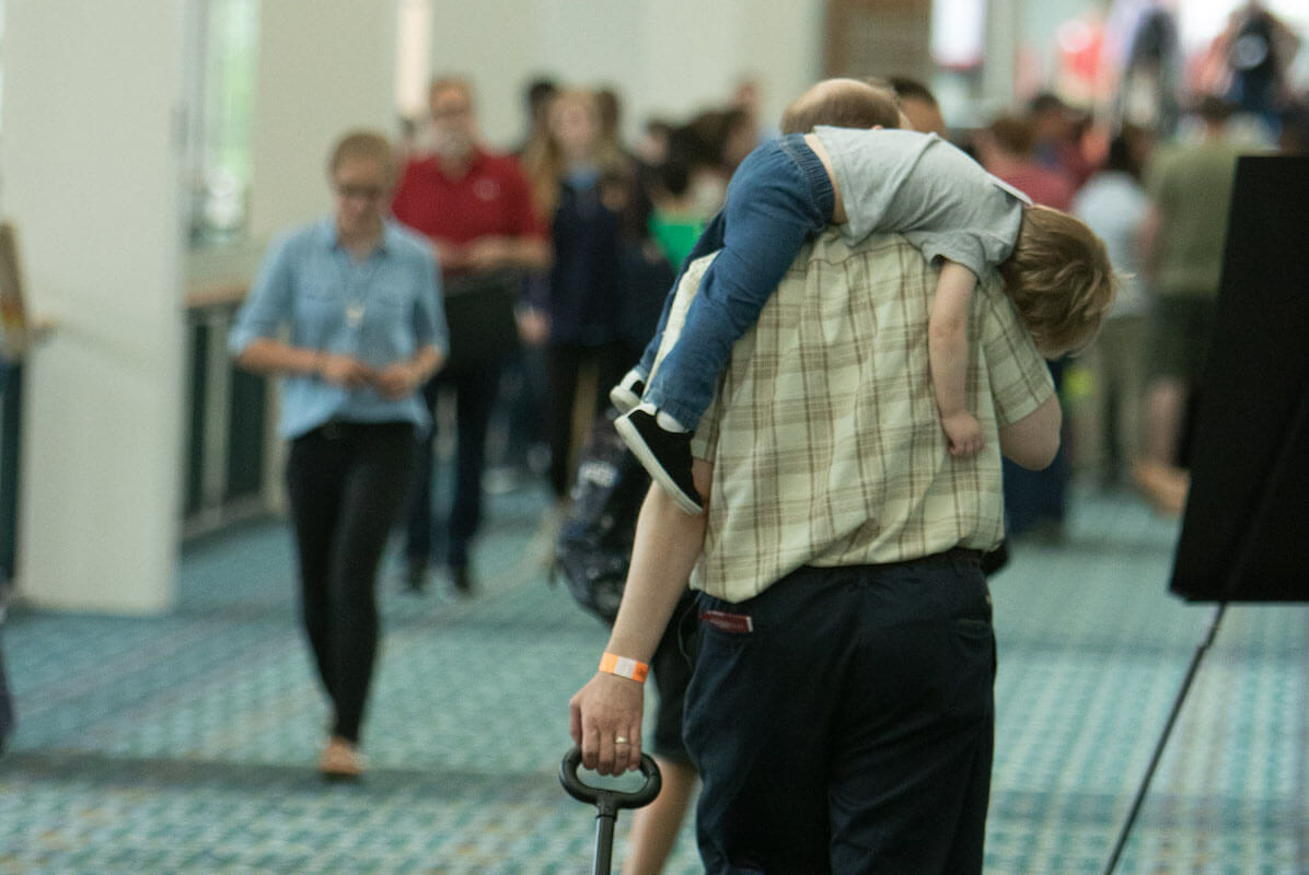 convention-father holding sleeping son on shoulder in foyer