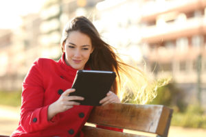 Woman red coat- reading tablet in park