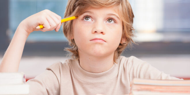 boy thinking with pencil against head