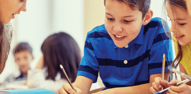 boy and girl writing with teacher in a group