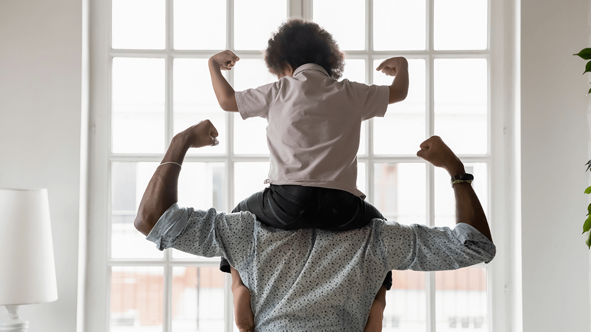 boy on shoulders of father pumping fists